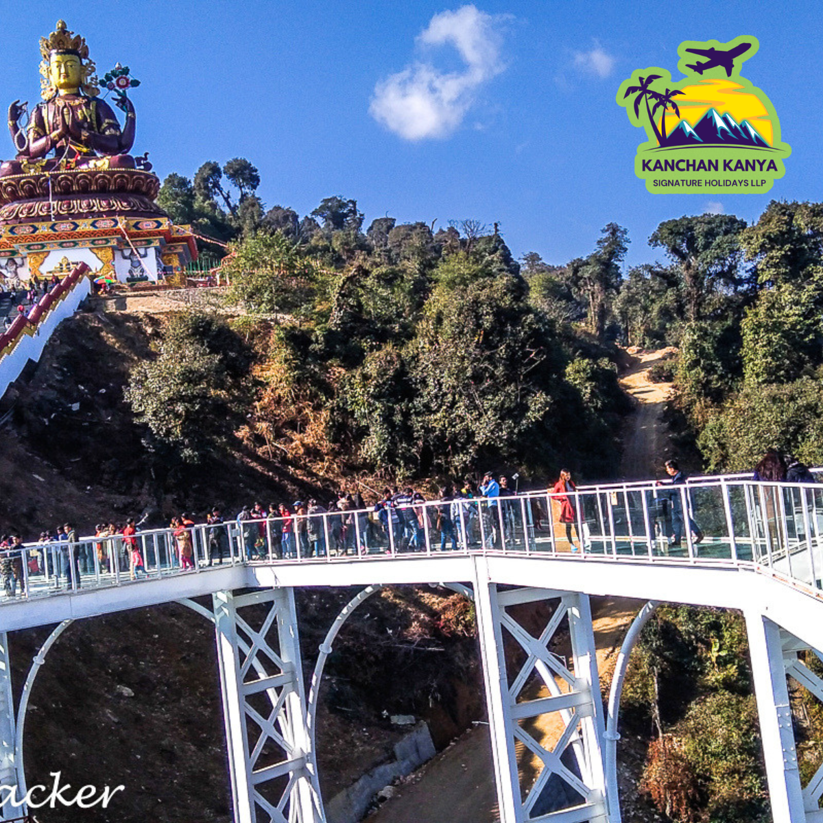 Bridge with pedestrians spanning a valley, a large ornate statue on a hill to the left, and a bright logo in the sky on the right.