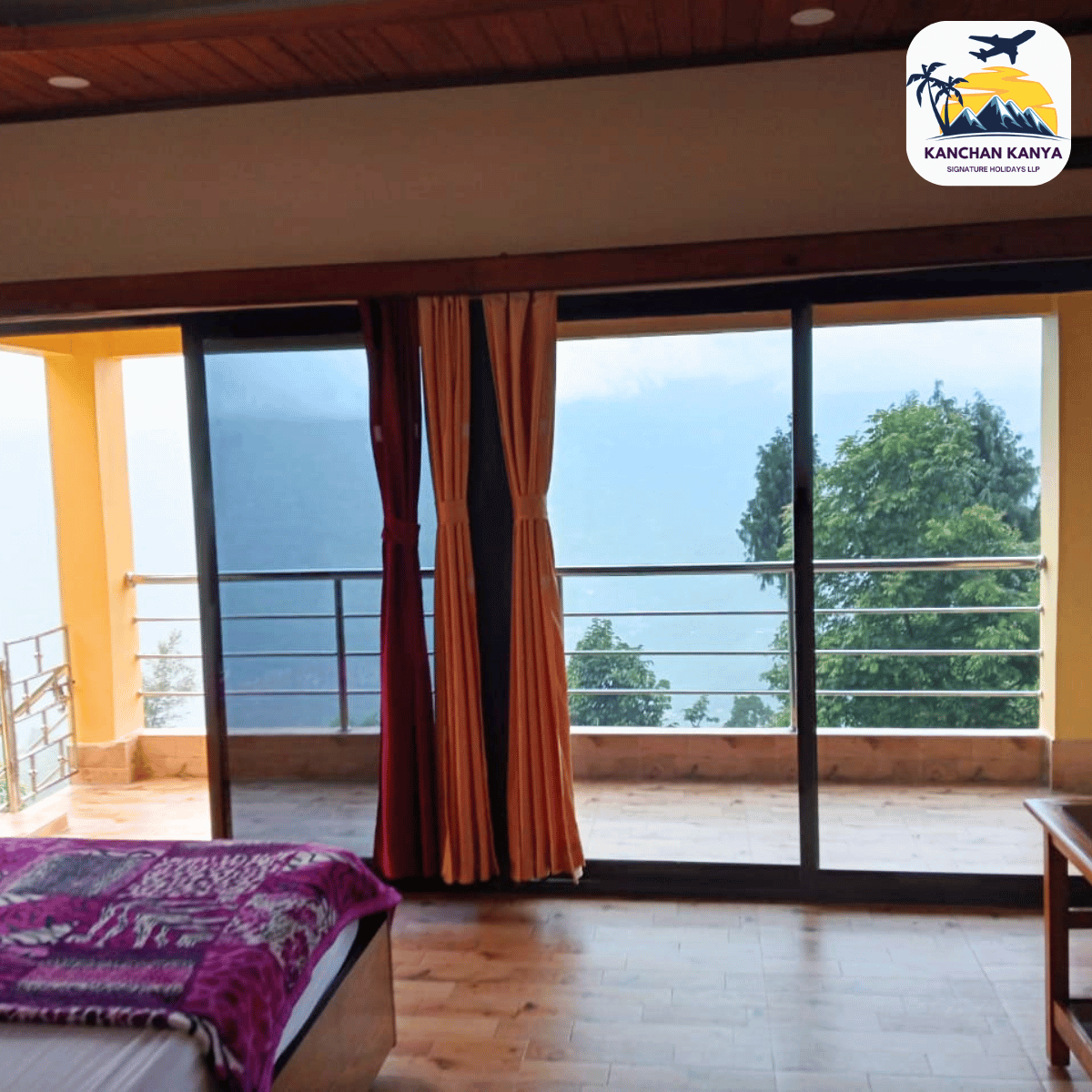 Hotel room with a glass balcony door revealing a valley and trees; bed with a purple blanket in the foreground.