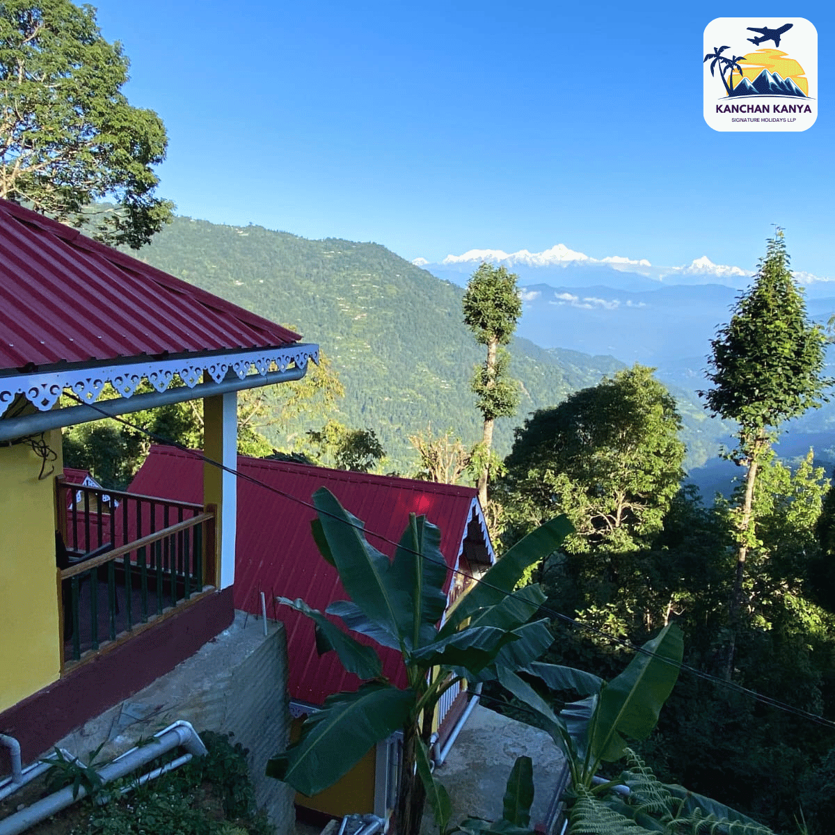 Hillside village with red-roofed houses, banana plants in the foreground, and distant snow-capped mountains under a blue sky; travel logo top-right.
