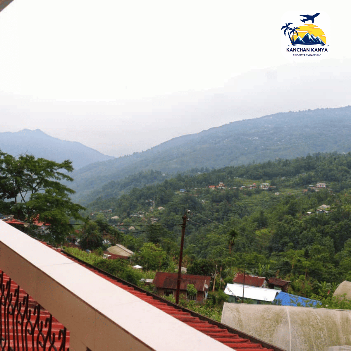 View over a green, mountainous valley with scattered houses and trees; travel logo in the top-right corner reads 'Kanchan Kanya Signature Holidays LLP'