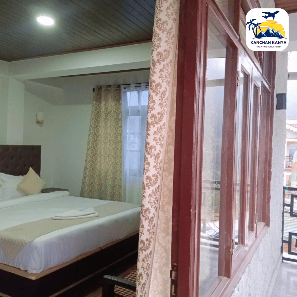 11 Hotel room with a large bed, white linens, beige throw, patterned curtains, and a wooden-framed window opening to a balcony.