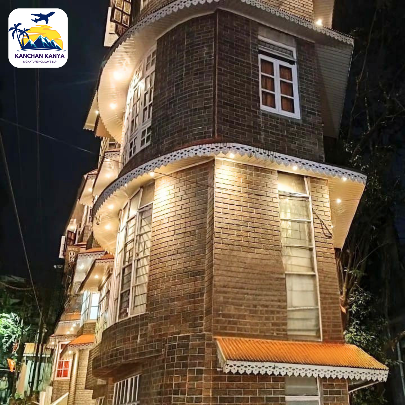 Night view of a brick hotel building at night with warm string lights and white decorative trim along the eaves.