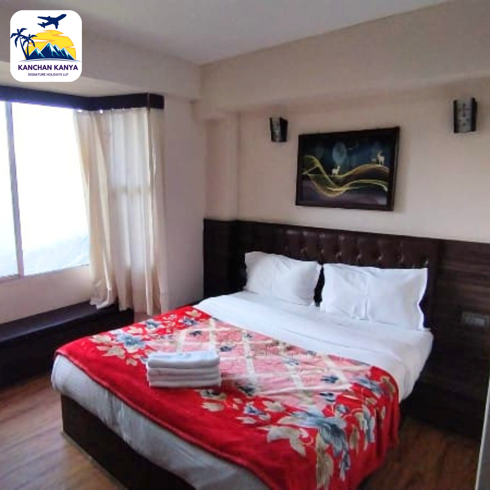 Hotel room with two twin beds, white linens and red floral bedspreads, towels folded at the foot, wall art, and a large window with sheer curtains.